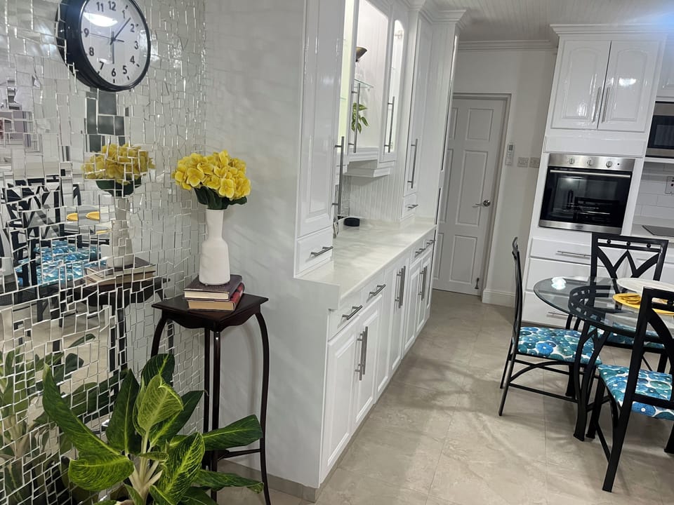 Mirrored wall with antique table and plant with a view to the kitchen/dinning 