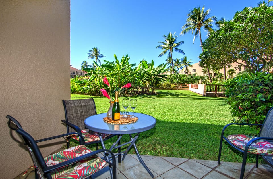 Sunset Ocean view beyond lanai with 4 chairs and table.