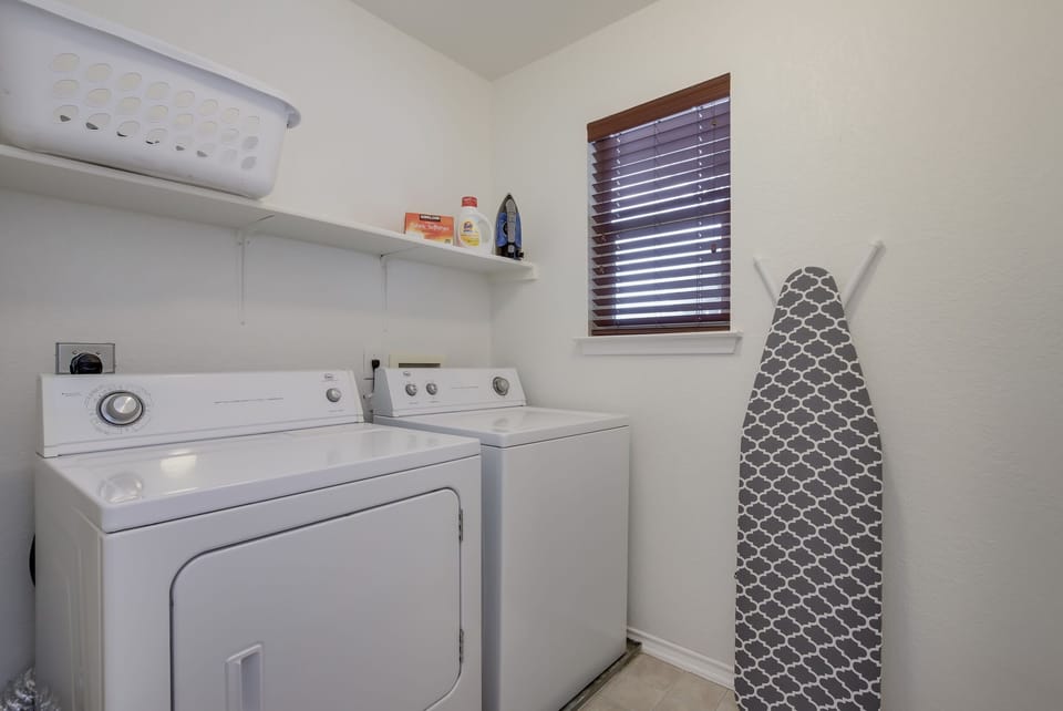 Utility room with washer, dryer, iron and ironing board.