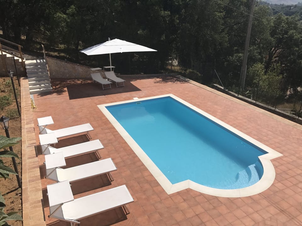 Swimming pool has sun loungers, umbrella and seating