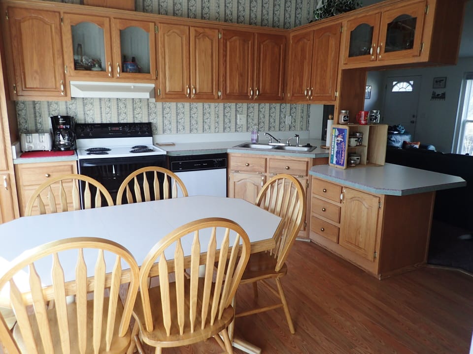 View from laundry room of kitchen & dining area, chairs for 6 at table.