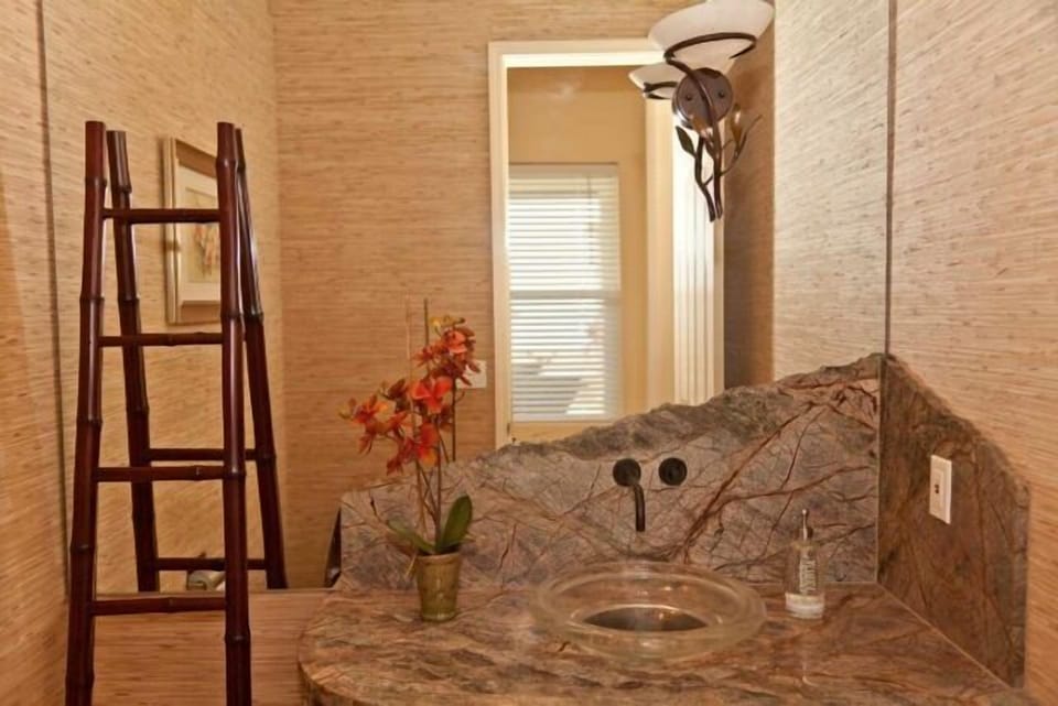 Guest bathroom has upgraded grass wall paper, sink, cabinet, and granite top