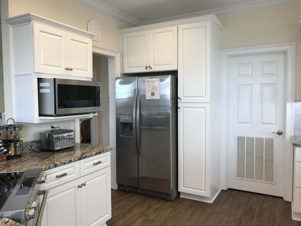 Full-size refrigerator/freezer with water and ice dispenser, laundry room door.