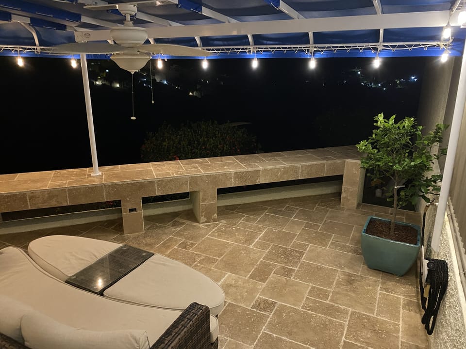 Big fixed awning covering majority of patio along with outdoor fan and lights.