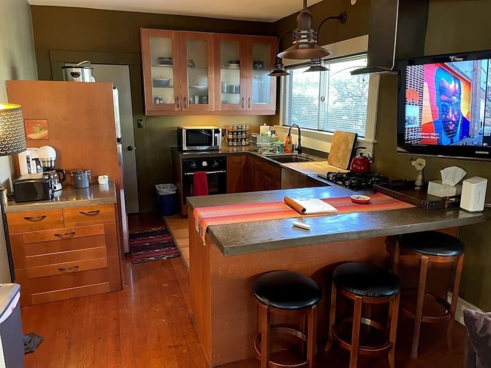 Kitchen with TV, Microwave, fridge, dishwasher, oven, coffee station and sink.