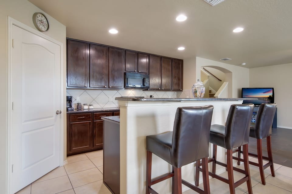 Alternate view of kitchen and bar seating area.