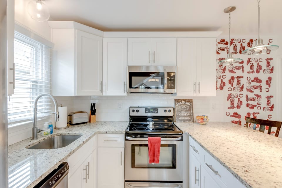 Stainless stove and microwave with quartz counters and bold accent wall