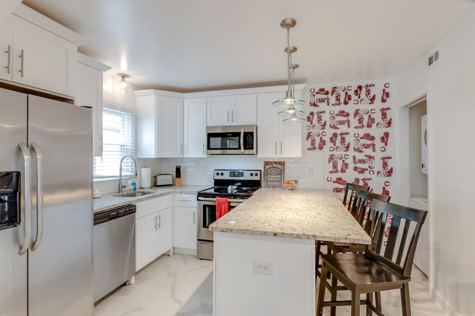 Bright white kitchen with granite island seating and pendant lights