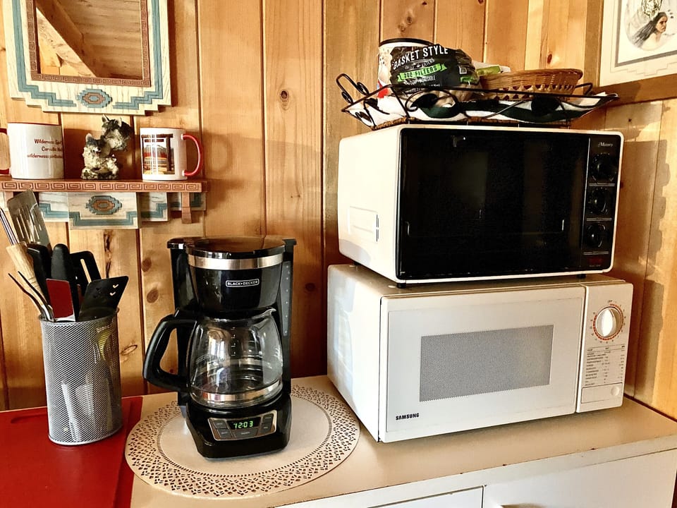 Close up of coffee maker, microwave, toaster oven with cook utensils, coffee.