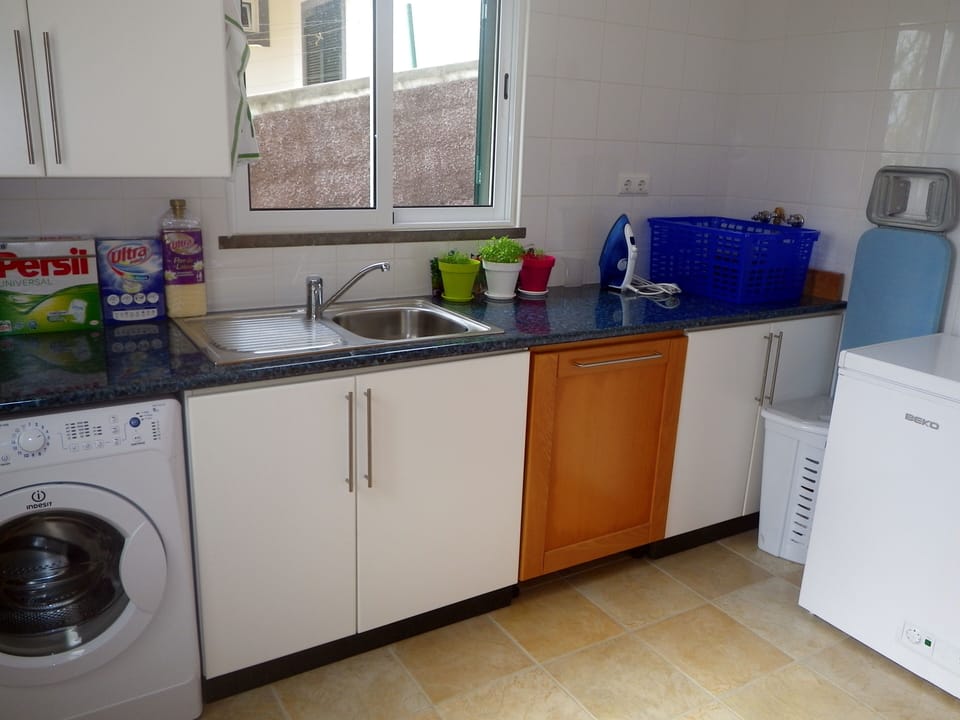 Laundry room with freezer, iron, ironing board and washing machine.