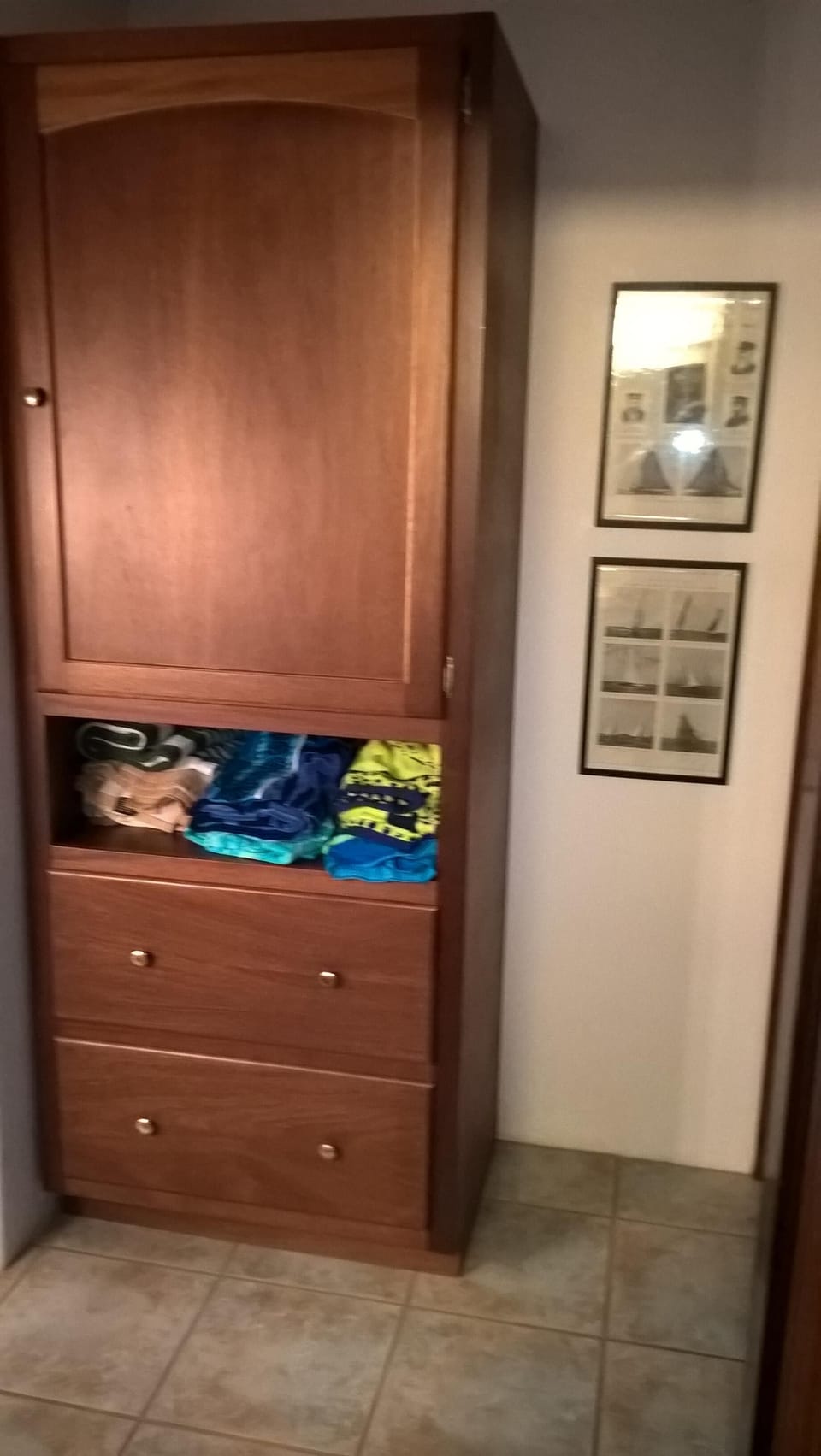 Vanity area has an armoire with clothes closet & drawers with Americas Cup art