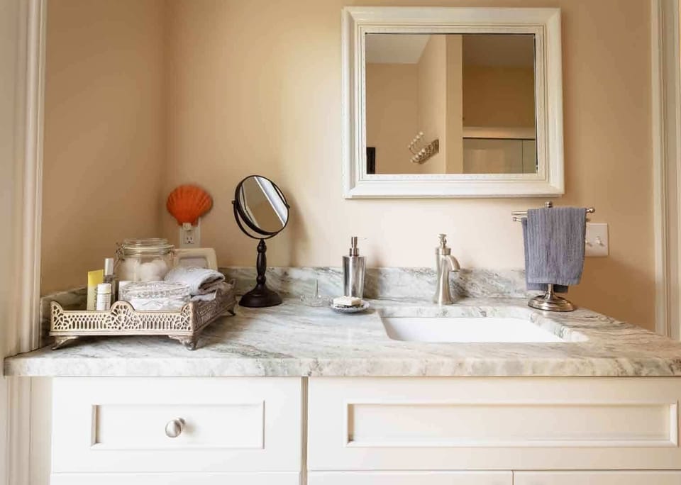 Guest bathroom with mirror, stainless steel fixtures and marble countertop.