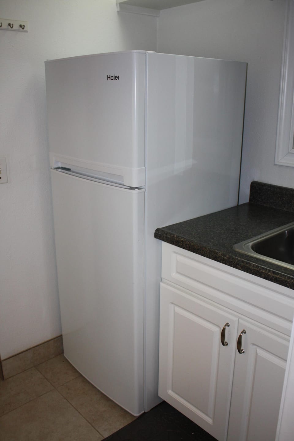 Galley kitchen has large sink and family size refrigerator with separate freezer