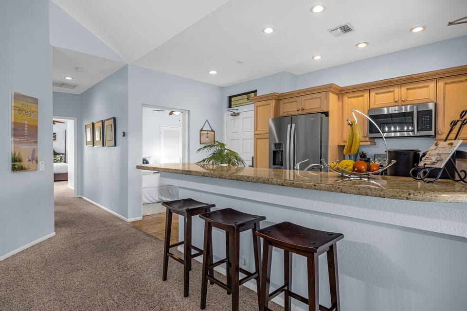 Comfortable bar seating along the granite counter creates an inviting space for meals, snacks, or conversation