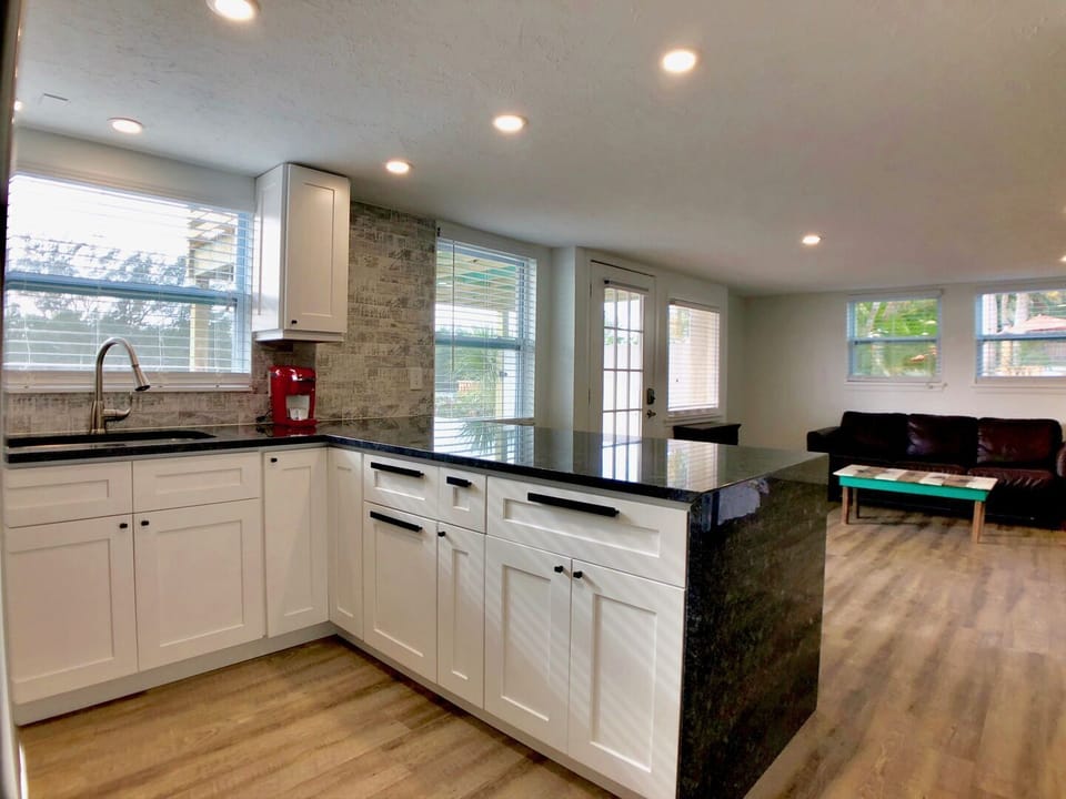 Kitchen with white cabinets, dark stone countertops, farmhouse sink, and windows