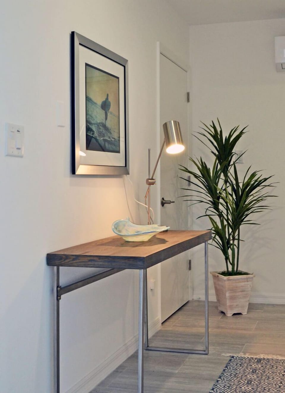 Bedroom desk and workspace area with lamp, tropical plant, and coastal artwork