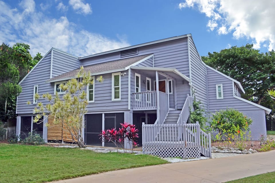 Front facade of the two-story treehouse-style home with dark wood shingles and lush landscaping