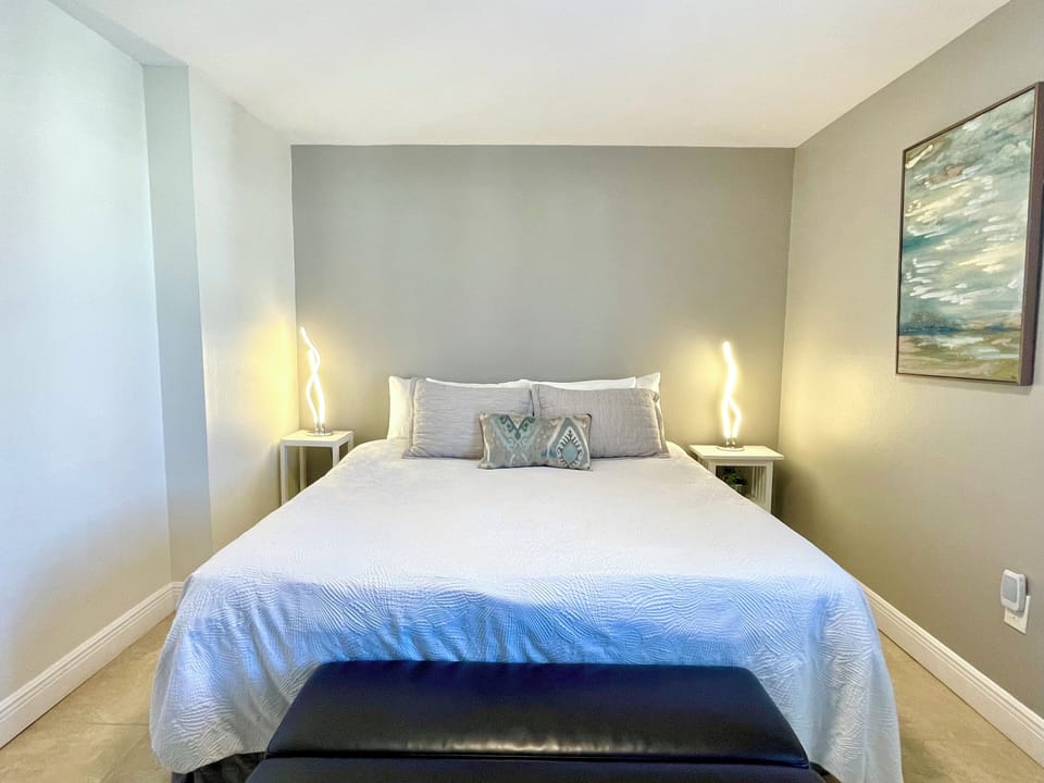 Guest bedroom with bedside lamps and coastal artwork