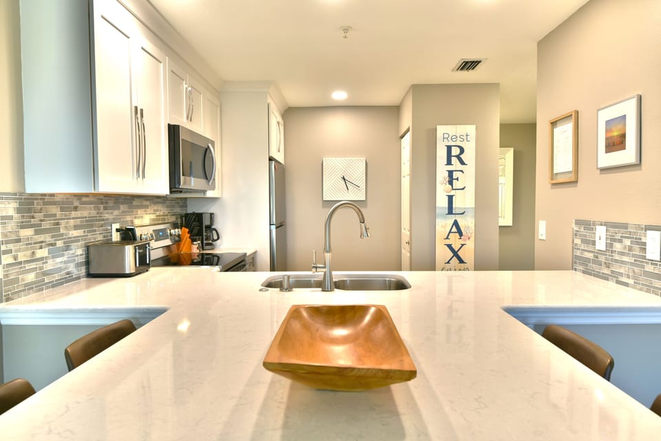 Kitchen with white cabinetry, stone tile backsplash, and stainless appliances