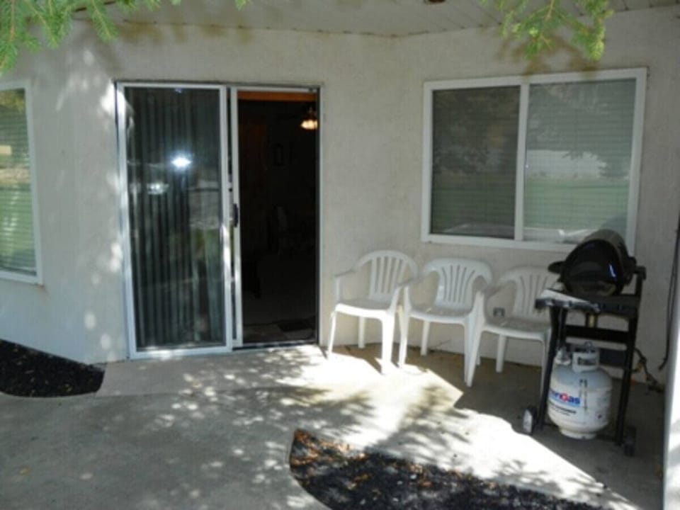 Cozy shaded patio with seating and a grill—perfect for outdoor meals and relaxing chats.