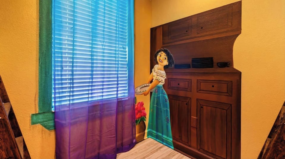 Whimsical room corner with a mural of a cheerful girl holding a plate, colorful curtains, and a sunny window.