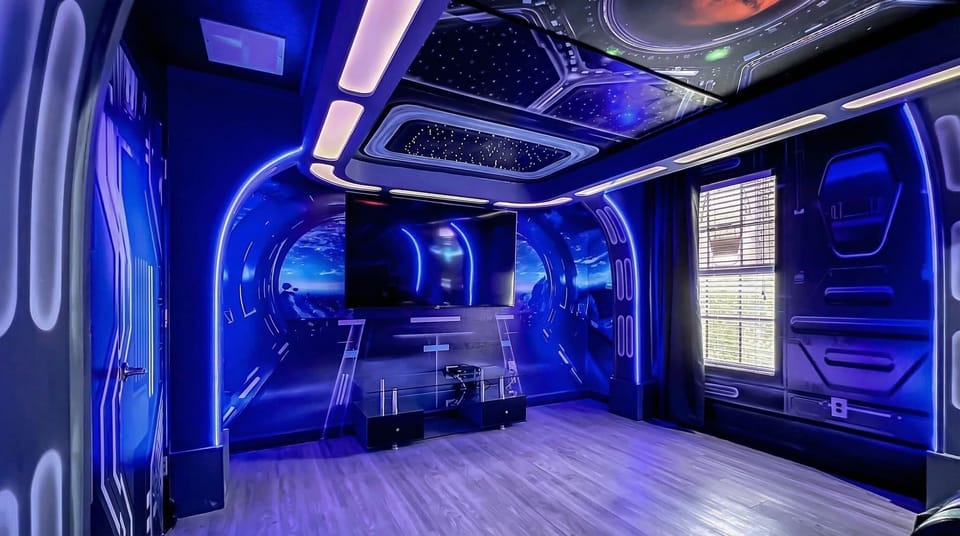 Futuristic entertainment room with a cosmic theme, ambient lighting, and a large screen for immersive viewing.