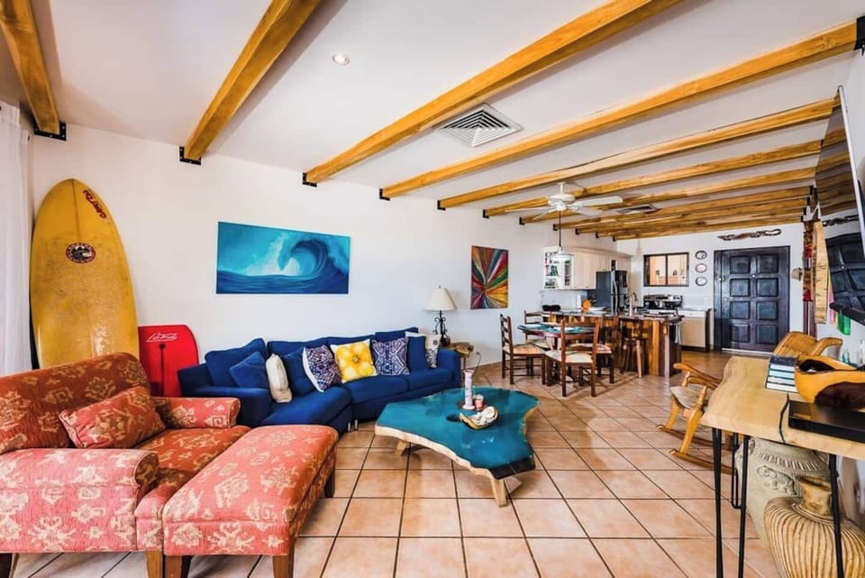 "Chic living room with comfy sofa, tropical decor, and surf-inspired touches — a perfect spot to unwind after catching waves. This Tamarindo condo blends laid-back style and comfort just steps from the beach.