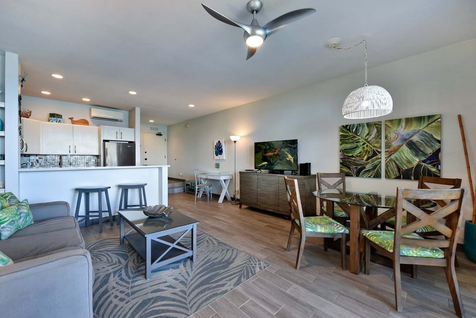 Perfect for entertaining, this open area pairs a glass-top dining table with kitchen counter bar seating and cool overhead ceiling fans.