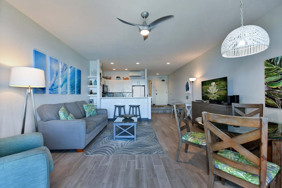 A broad view showcasing the seamless layout connecting the living room, kitchen, dining area, and entryway in one continuous, airy space.
