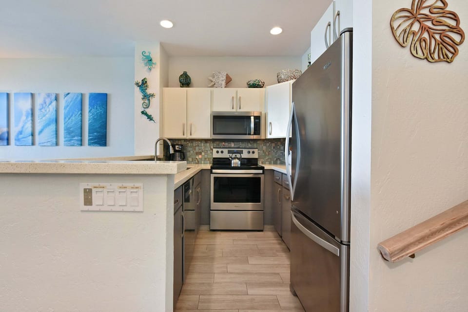 Cook with ease in this updated kitchen featuring sleek stainless steel appliances, solid counter space, bright white cabinetry, and a convenient breakfast bar.