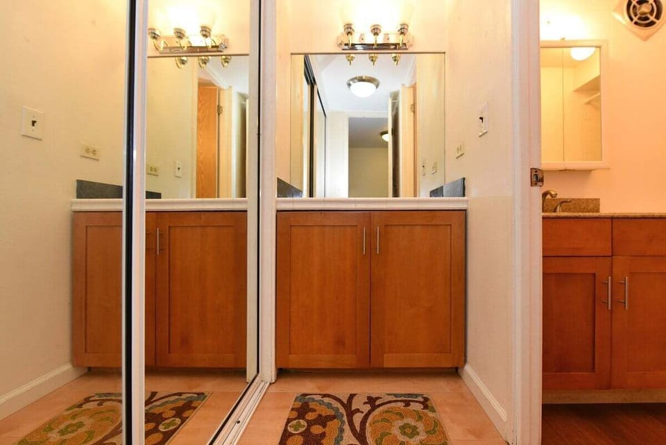 Dressing area with mirrored closet doors, granite countertop, and ample storage for a comfortable stay.