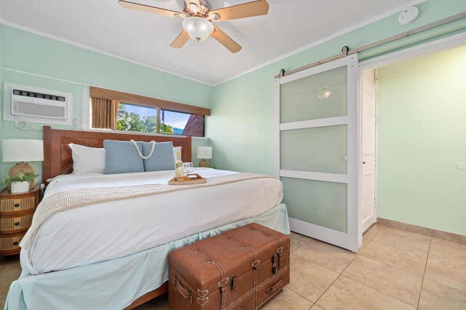 Primary bedroom with king bed, ceiling fan, and calming island colors.