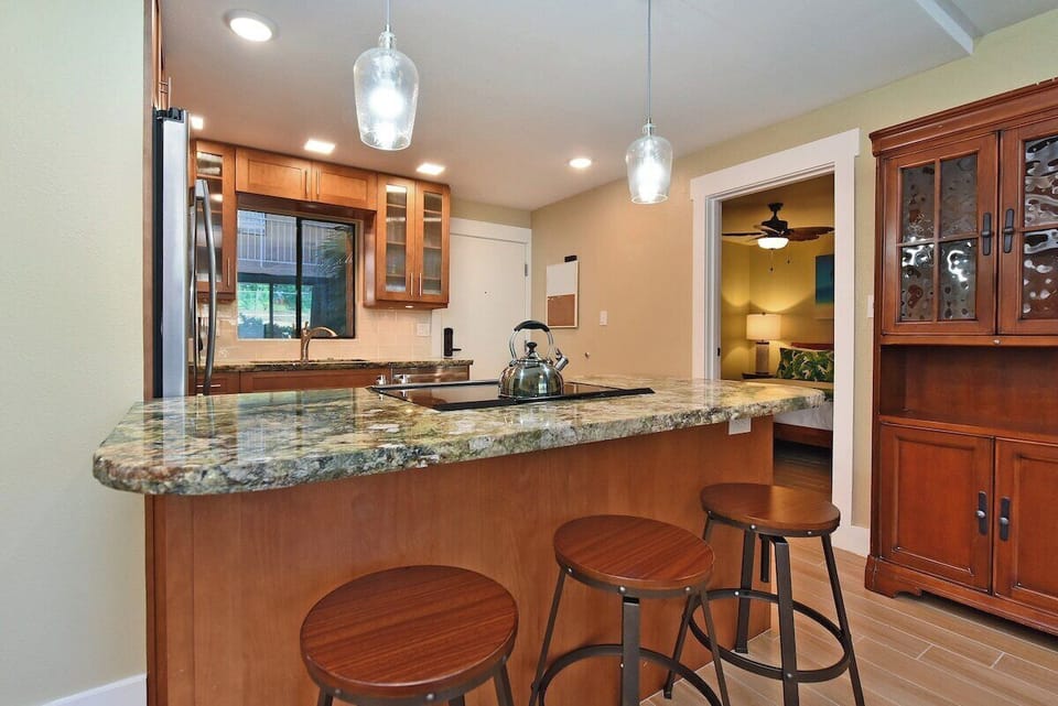 Kitchen island with granite counters, pendant lighting, and bar seating for three.