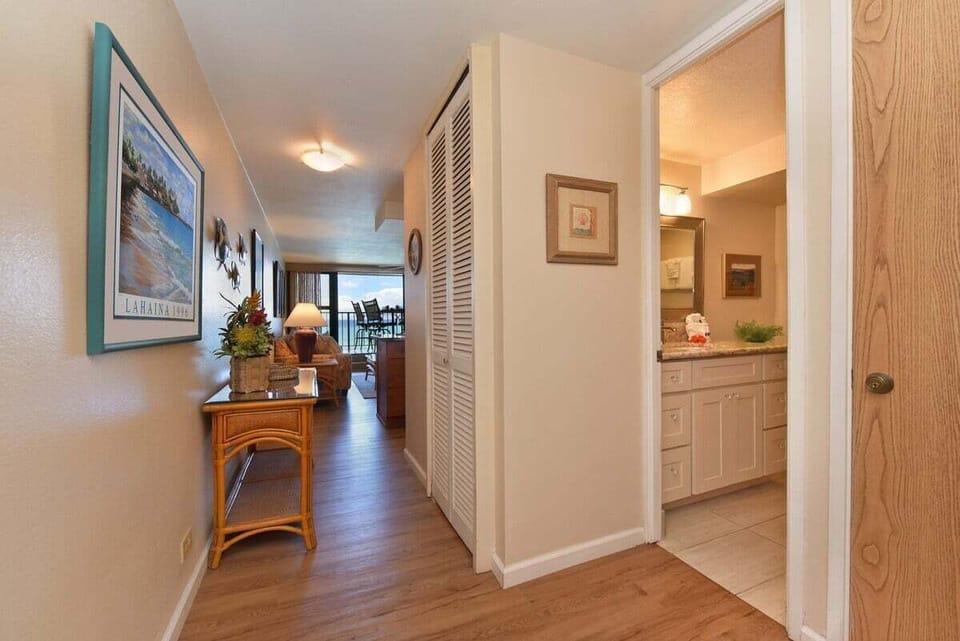 Inviting entryway with tropical décor, natural wood accents, and a glimpse of the spacious living room and balcony beyond