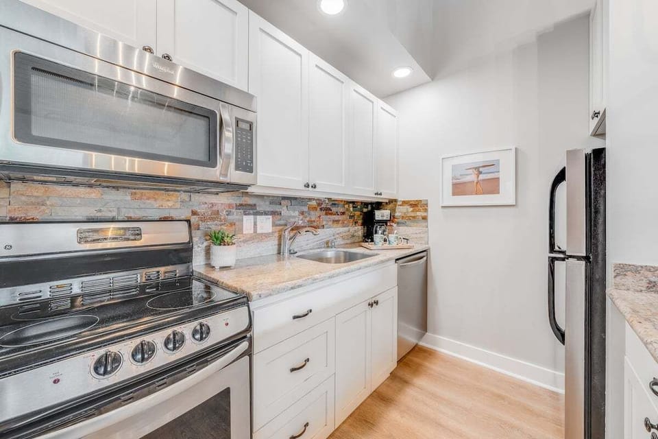 Cook with ease in a well-equipped kitchen featuring white cabinetry, tiled backsplash, and recessed lighting for a clean, contemporary feel.