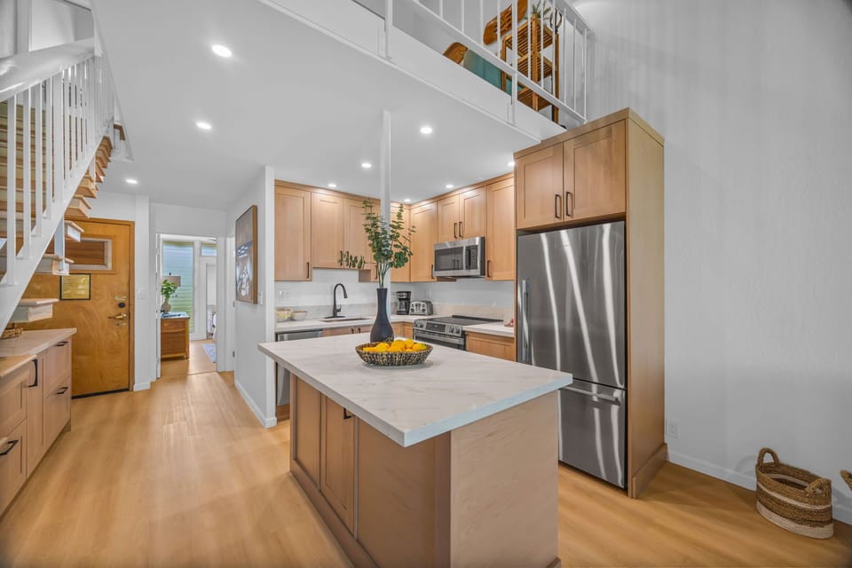 Featuring light-wood cabinetry, a large center island with quartz countertops, and high-end stainless steel appliances. This is your dream kitchen!