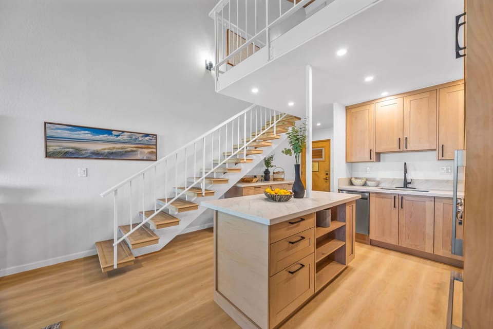 Ppen-concept space: from the luxurious kitchen island and modern cabinetry to the impressive staircase leading to the loft. The high ceilings and contemporary design create a truly exceptional vacation atmosphere.