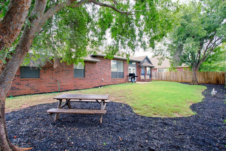 Backyard complete with a picnic table and chairs and a propane gas grill