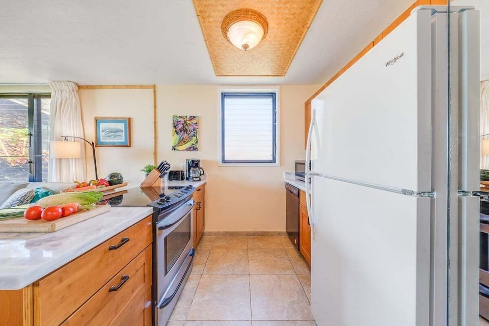 A bright kitchen with warm wood cabinetry, fresh ingredients on the counter, and natural light pouring in.