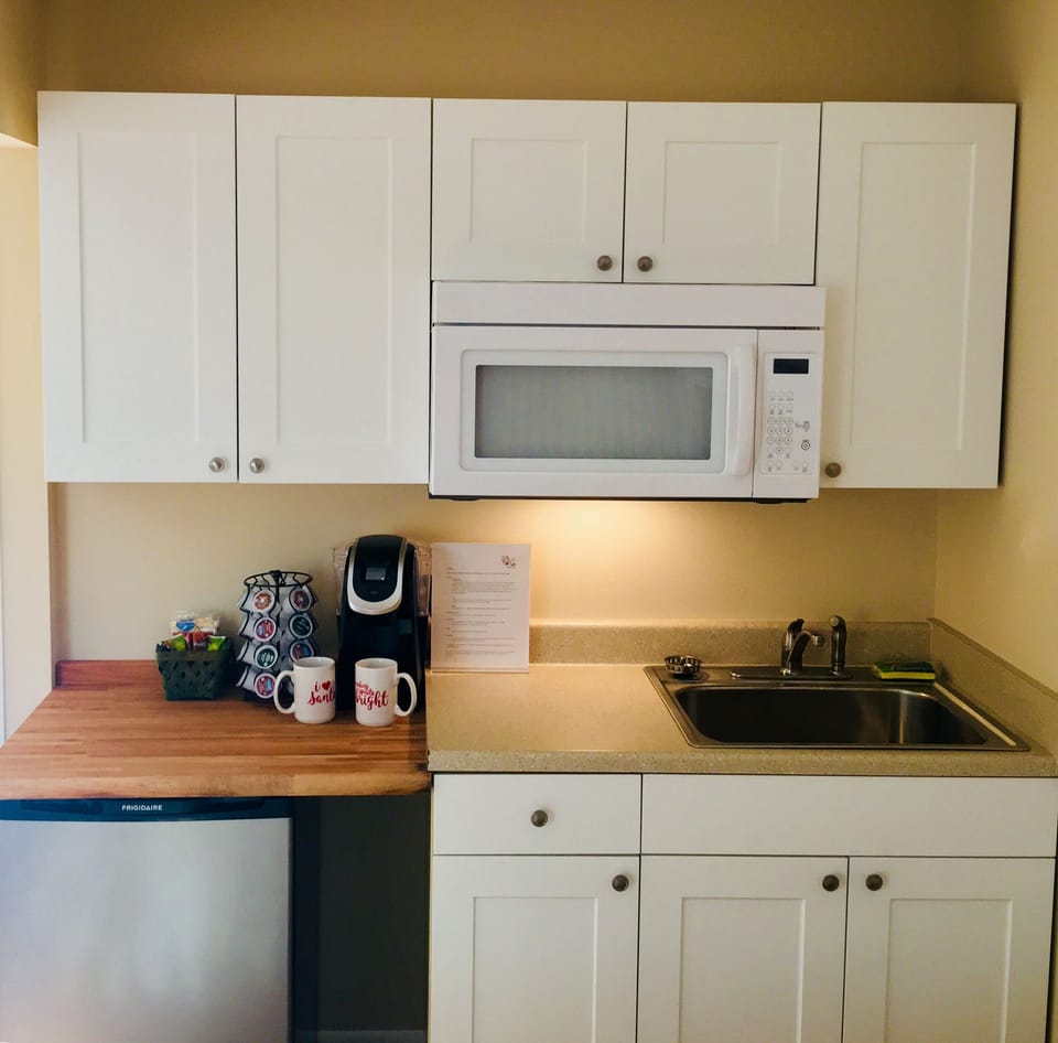 Kitchen has microwave, toaster oven, toaster, blender and dishes.