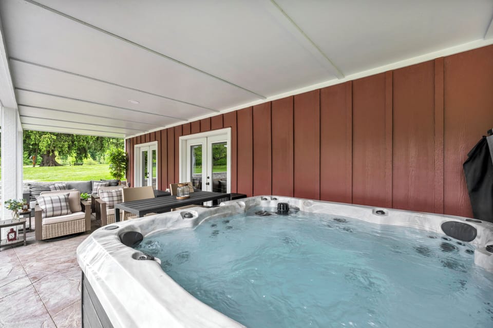 Hot Tub: Relax in a private covered hot tub surrounded by comfortable outdoor seating and peaceful natural views.