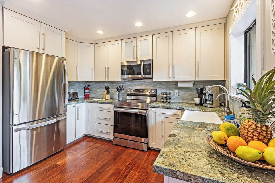 Modern kitchen with sleek stainless steel appliances, white cabinetry, and granite countertops. Bright and open, this space offers plenty of room for cooking and entertaining, complete with island-inspired design!