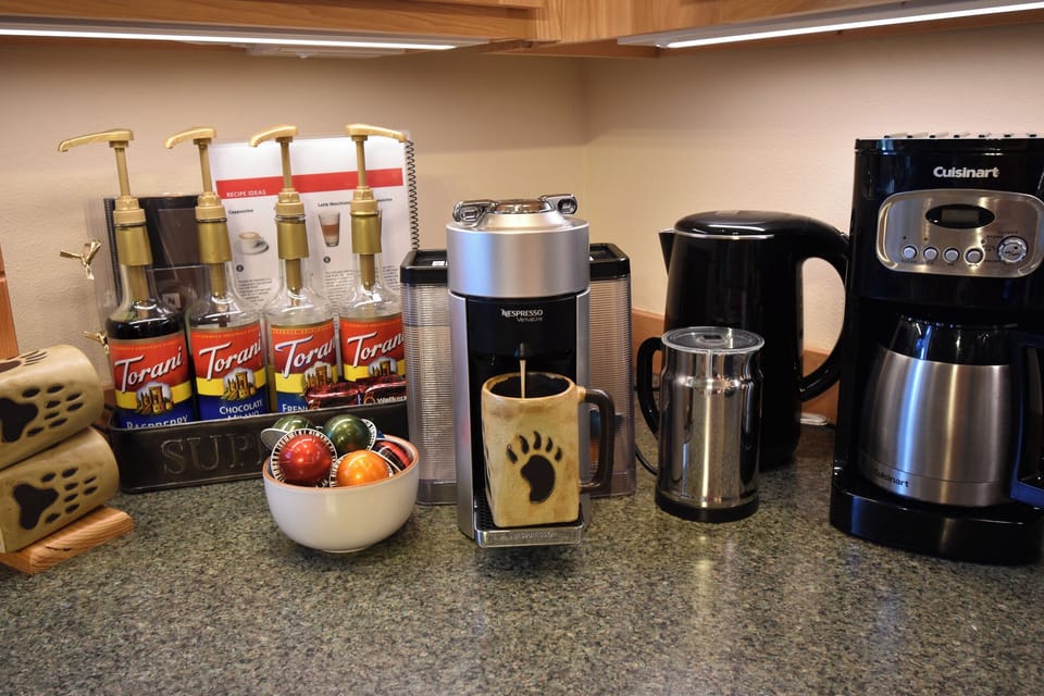 Coffee station with both an espresso machine and a 12-cup drip coffee maker, along with a variety of coffee syrups.