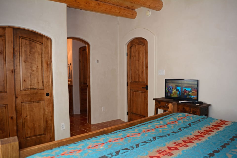 "2nd King Master bedroom" with flat screen satellite TV, shows sample of custom designed, hand crafted arched doors and door ways throughout every room & entry in the house + in-suite walk in shower bathroom