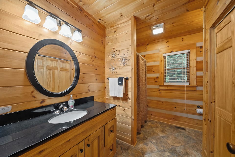 Warm knotty pine walls and a dark granite vanity give this bathroom a cozy cabin feel at Uncle Johns Cabin.