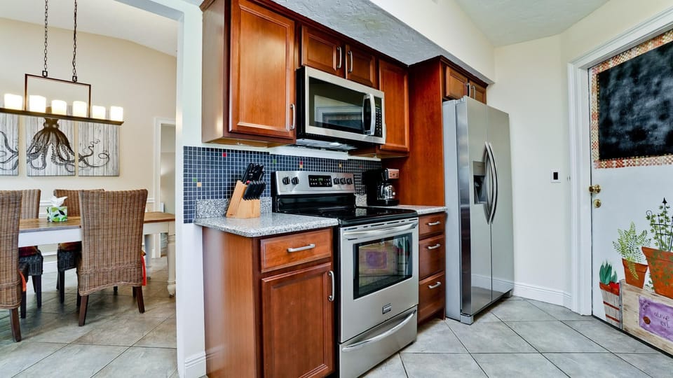 Kitchen features stainless steel appliances, dark wood cabinets, granite counters, and a mosaic tile backsplash.