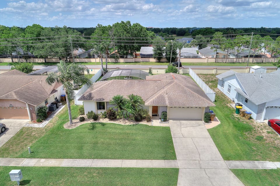 Spacious front yard and driveway in a peaceful neighborhood with plenty of greenery.