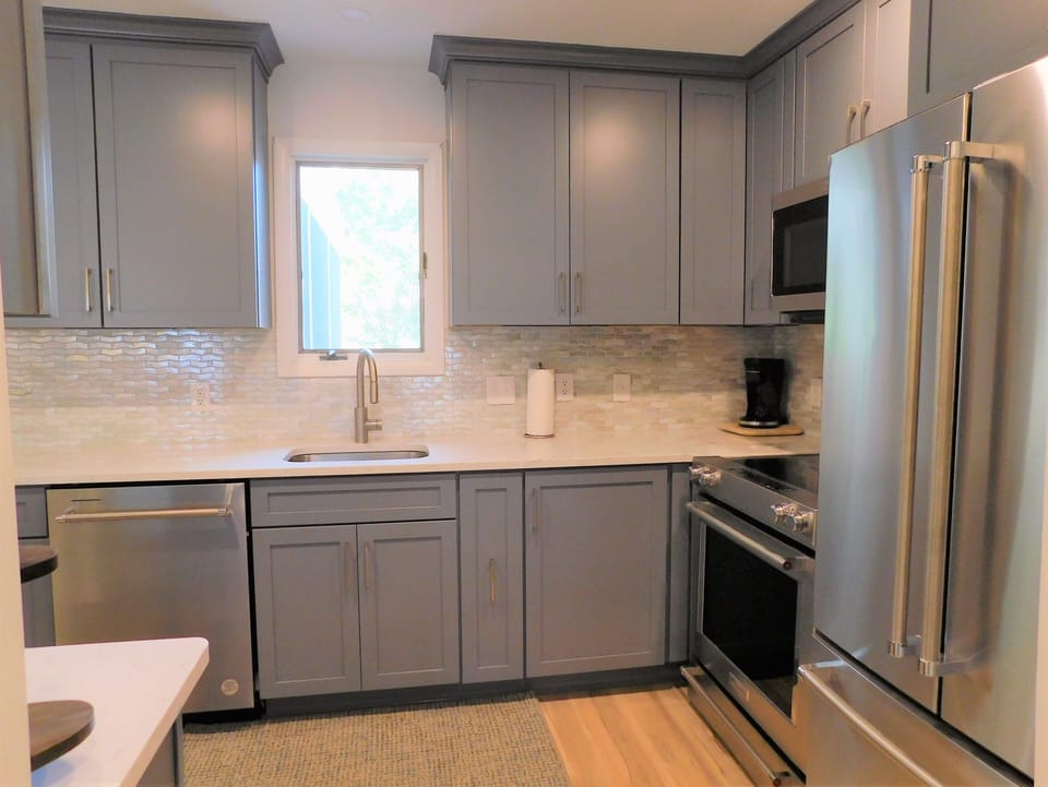 414 Bethany Pines, Bethany Beach - Kitchen detail - Perspective of the kitchen highlighting the slate blue cabinetry, stainless steel refrigerator, and white countertops.