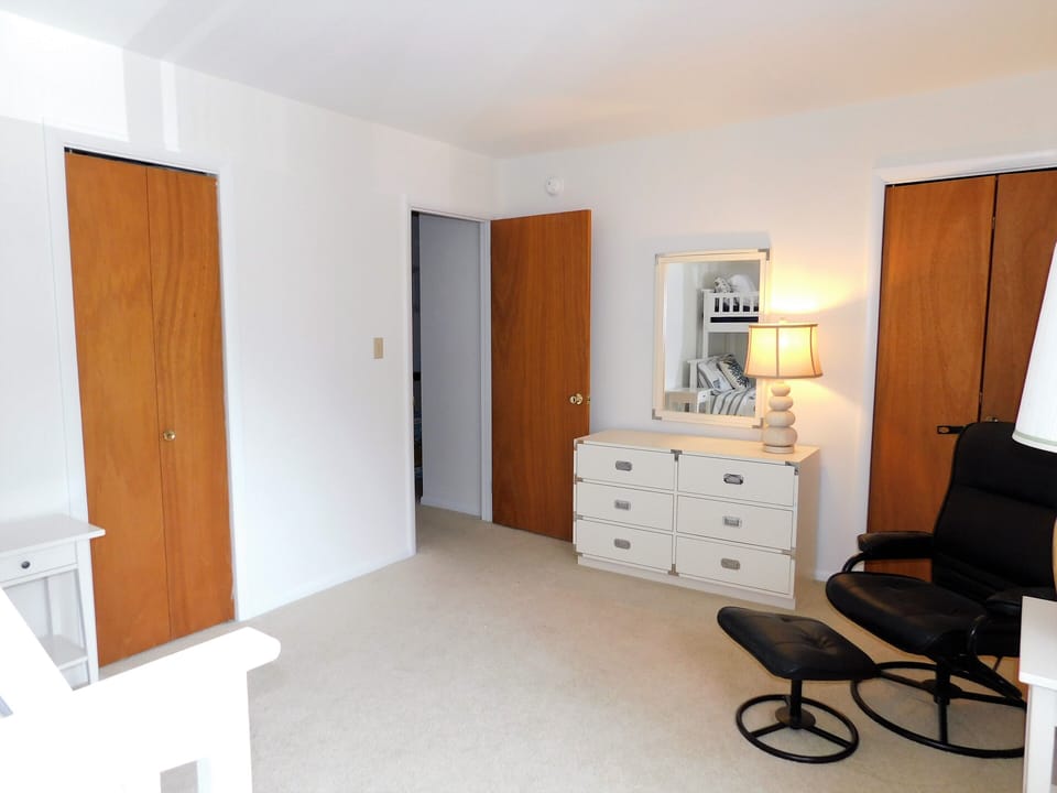 414 Bethany Pines, Bethany Beach - guest bedroom storage - View of the guest room highlighting the wooden dresser, armchair, and closet space.