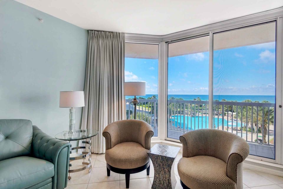 Tiled living room with view of community pool and Gulf